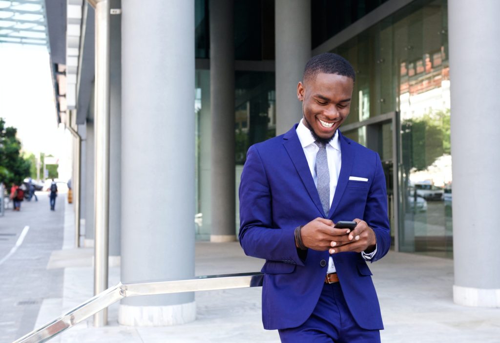 African business man walking and looking at mobile phone